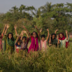 Nour (12) ist mit ihren Freundinnen unterwegs zwischen Reisfeldern, die ihr Wohnviertel säumen.